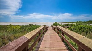 A wooden boardwalk leading to a beach with clear skies.