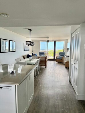 A modern kitchen with a dining area, a view of the sea, and a balcony with seating.