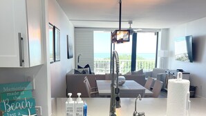 A modern kitchen with a central island, a built-in sink, and a dining area with a sofa and table.