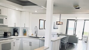 A modern kitchen with white cabinets, a central island, and a dining area with a view.