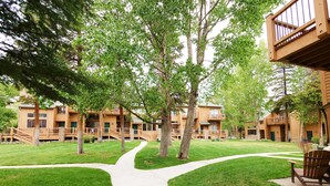 A pathway leading to a building with multiple balconies and a stone wall. - Beautiful Ski In/Out Cedars Townhome with Private Hot Tub (Breckenridge)