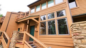 A two-story wooden house with a stone staircase and a balcony. - Beautiful Ski In/Out Cedars Townhome with Private Hot Tub (Breckenridge)