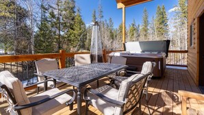 Une terrasse extérieure avec une table et des chaises, un barbecue et un jacuzzi.