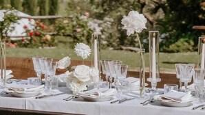 A table set outdoors with white flowers and clear glassware, set against a backdrop of greenery and trees. - Villa San Lorenzo - Large private farmhouse style villa (Grezzano)