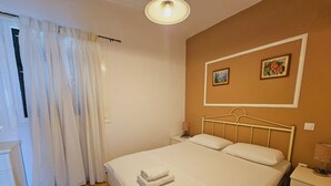 A bedroom with a bed, a nightstand, a lamp, and two framed pictures on the wall. - Corfu Dream Holidays  Apartments (Corfu)