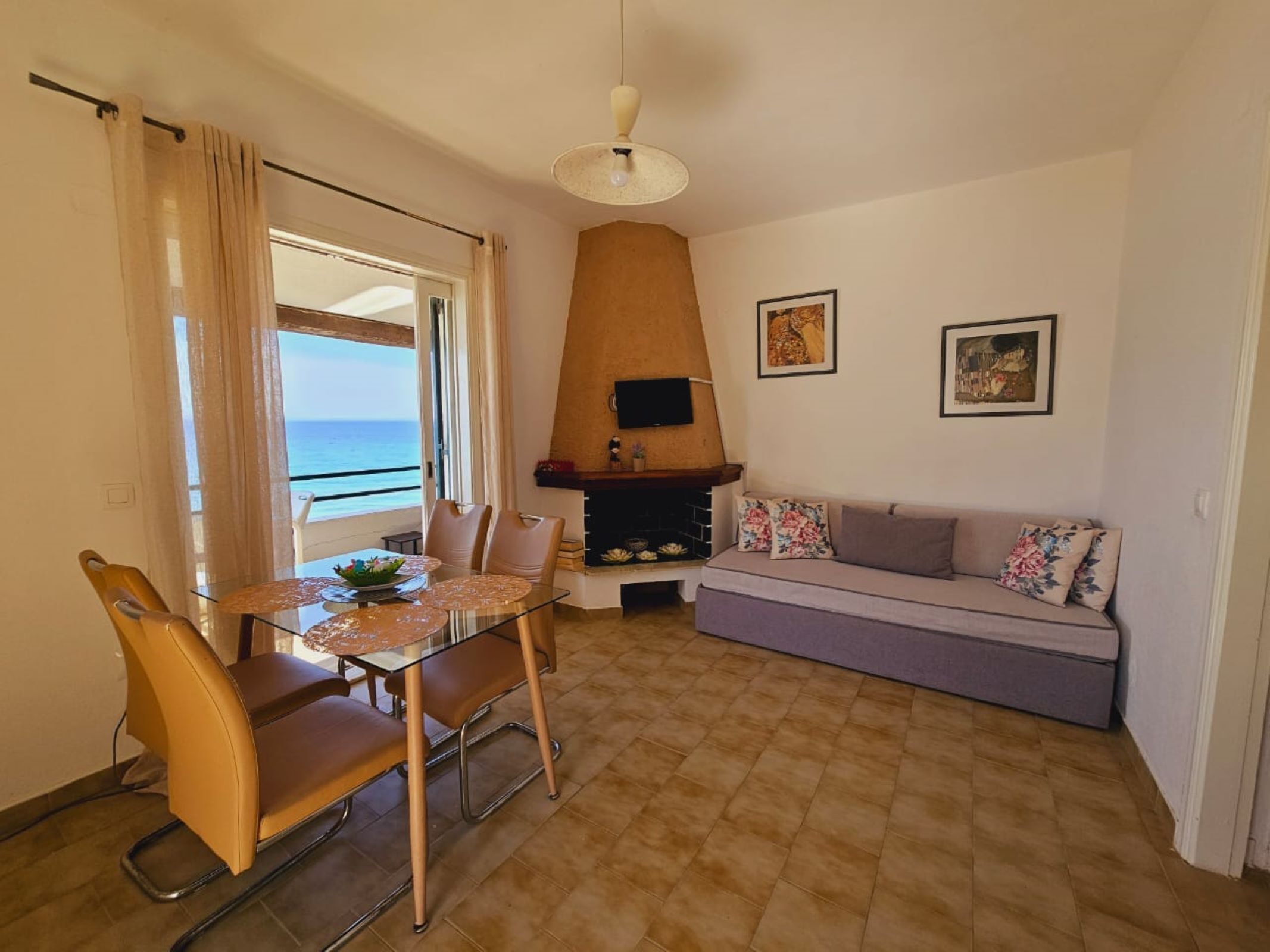 Un espace repas comprenant une table et des chaises, un canapé, une cheminée et une vue sur la mer.