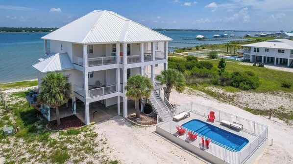 A multi-story beachfront property with a pool and a view of the water.