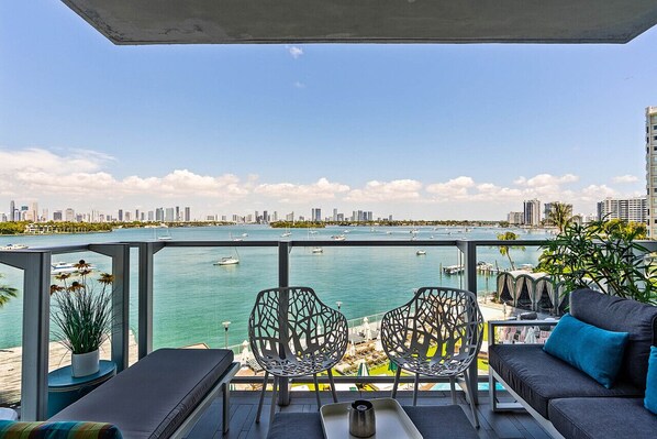 Enjoy the marina view from this balcony with a sofa, chairs, and a small table.