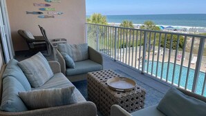 A balcony with wicker furniture, a view of the ocean, and a pool area. - Hamilton 202, Oceanfront, Litchfield by the Sea (Pawleys Island)