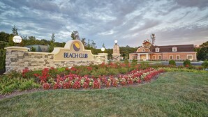 Schild eines Beachclubs, mit einer Steinwand und einem angelegten Garten mit bunten Blumen.