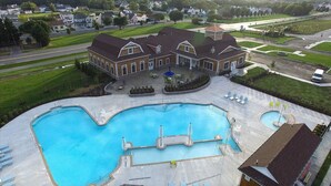 Ein großer Pool mit einer Fontäne, umgeben von einer Terrasse mit Liegestühlen und Sonnenschirmen.