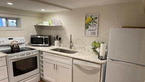 A kitchen with white cabinets, a stainless steel stove, a microwave, a sink, and a refrigerator. - The Pink House- minutes walk to beach!! (Galveston)