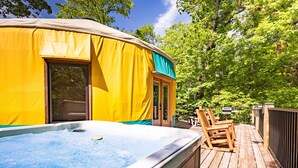 A hot tub on a wooden deck with a yellow and green covered structure in the background. - Comfy, Cozy, Luxury Yurt, Fun w/Private Hot Tub & Gas Grill, Large Deck (Pigeon Forge)