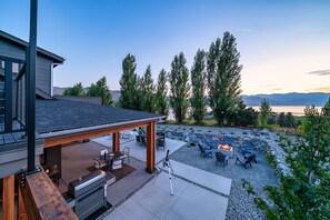 A modern outdoor patio with a grill, seating area, and a scenic view of mountains and a lake.