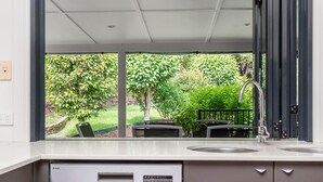 Une cuisine moderne dotée d’une grande fenêtre donnant sur un jardin.