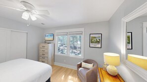 A bedroom with a bed, a dresser, a chair, a desk with a lamp, a ceiling fan, and a window with blinds. - Daydream Oasis with private pool, screen porch with dining, sleeps 8! (Isle of Palms)
