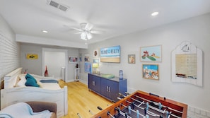 A room with a bed, a desk, a foosball table, and a TV on the wall. - Daydream Oasis with private pool, screen porch with dining, sleeps 8! (Isle of Palms)