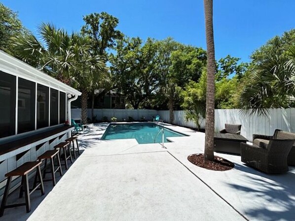 A backyard with a swimming pool, outdoor seating, and a covered area with bar stools. - Daydream Oasis with private pool, screen porch with dining, sleeps 8! (Isle of Palms)