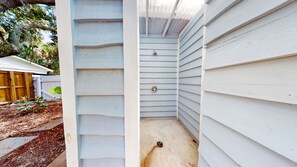 A narrow, enclosed outdoor area with light blue siding, a metal door, and a concrete floor. - Daydream Oasis with private pool, screen porch with dining, sleeps 8! (Isle of Palms)
