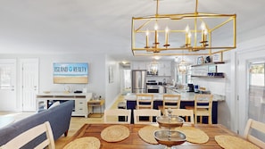 A modern kitchen with a central island, stainless steel appliances, and a dining area with a wooden table and chairs. - Daydream Oasis with private pool, screen porch with dining, sleeps 8! (Isle of Palms)