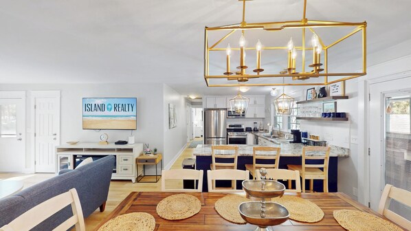 A modern kitchen with a central island, stainless steel appliances, and a dining area with a wooden table and chairs.