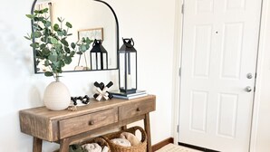 A wooden console table with baskets, a mirror, and decorative items.
