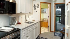 A modern kitchen with white cabinets, stainless steel appliances, and a patterned rug. - Balcony with Lake Michigan and golf view (Cedar)