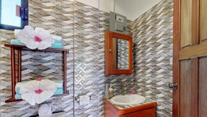 A bathroom with a patterned tile backsplash, a wooden vanity, a sink, and a mirror. - comfortable stay! perfect location amazing sun and reef view (BELIZE)