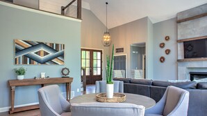 A modern living room with a sectional sofa, a round coffee table, and a decorative plant. - Luxury Estate w/ Hot Tub & Game Room + Biltmore Pass | 18 Min to Asheville (Asheville)