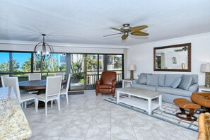 A spacious living area with a dining table, chairs, a sofa, a coffee table, and a ceiling fan. - Firethorn 210- Beautiful gulf side, ground-level 2BR/2BA unit! (Sarasota)