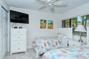 A bedroom with a bed, a dresser, a television, and a ceiling fan. - Firethorn 210- Beautiful gulf side, ground-level 2BR/2BA unit! (Sarasota)