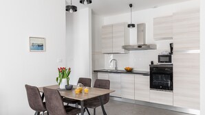 A modern kitchen with a dining area. It includes a wooden table with chairs, a sink, a stove, and a microwave. - Apartments Villa Salona Sky - Premium One Bedroom Apartment with Balcony (Solin)