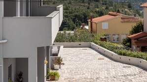 A modern building with a tiled roof, a balcony, and a view of mountains. - Apartments Villa Salona Sky - Premium One Bedroom Apartment with Balcony (Solin)