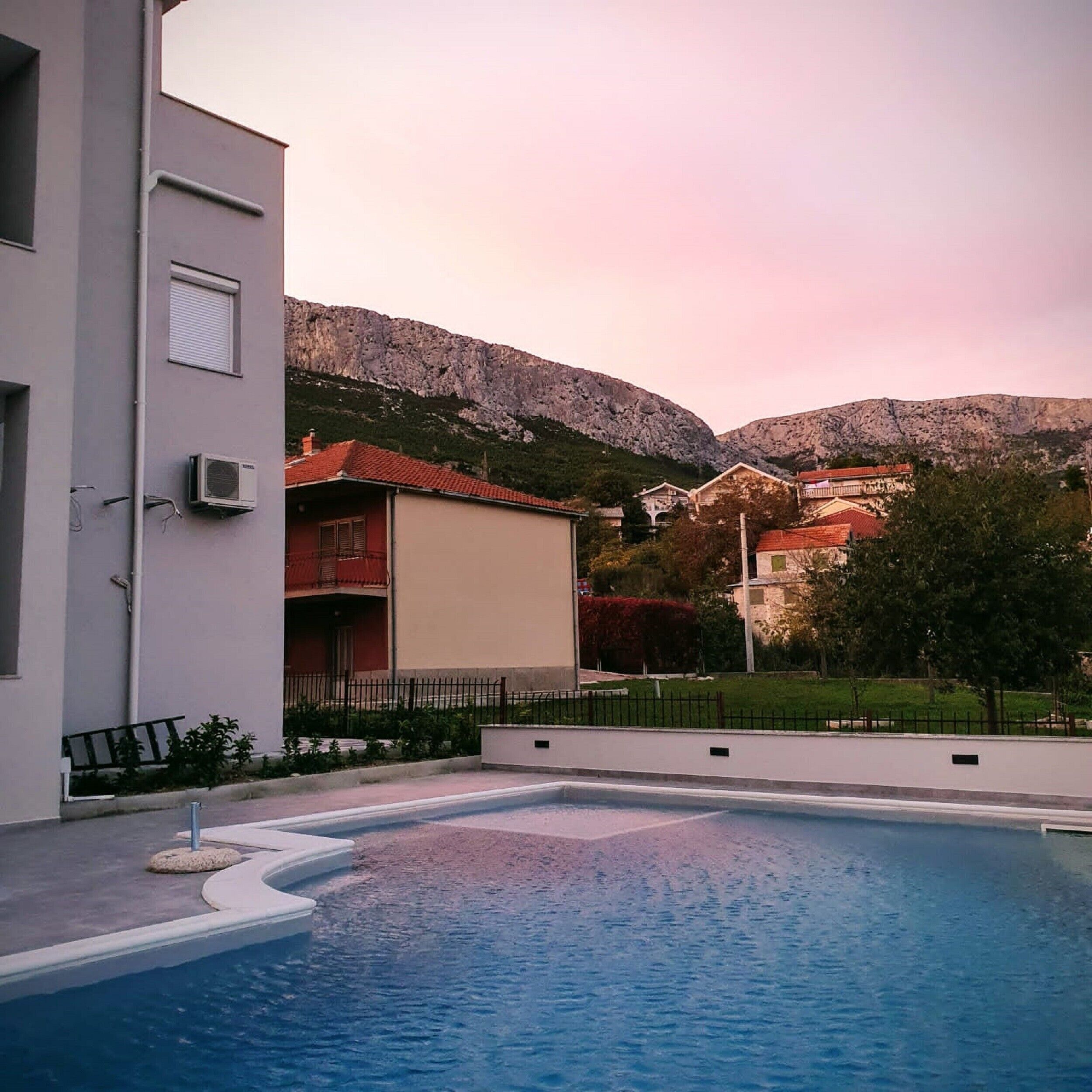 A swimming pool with a view of a mountain and residential buildings in the background.