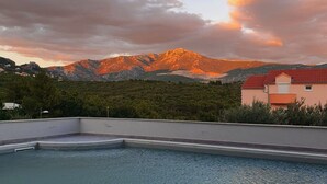 A swimming pool with a view of mountains and a building in the background. - Apartments Villa Salona Sky - DeluxeTwo Bedroom Apartment with Balcony (Solin)