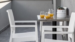 A balcony with white wicker chairs and a table, a potted plant, and a view of mountains. - Apartments Villa Salona Sky - DeluxeTwo Bedroom Apartment with Balcony (Solin)