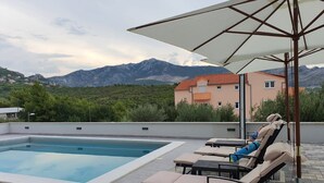 A rooftop pool area with lounge chairs and an umbrella, overlooking a mountainous landscape. - Apartments Villa Salona Sky - Superior Two Bedroom Apartment with Balcony (Solin)