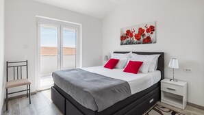 A bedroom with a bed, a chair, a nightstand, and a window. - Apartments Villa Salona Sky - Superior Two Bedroom Apartment with Balcony (Solin)