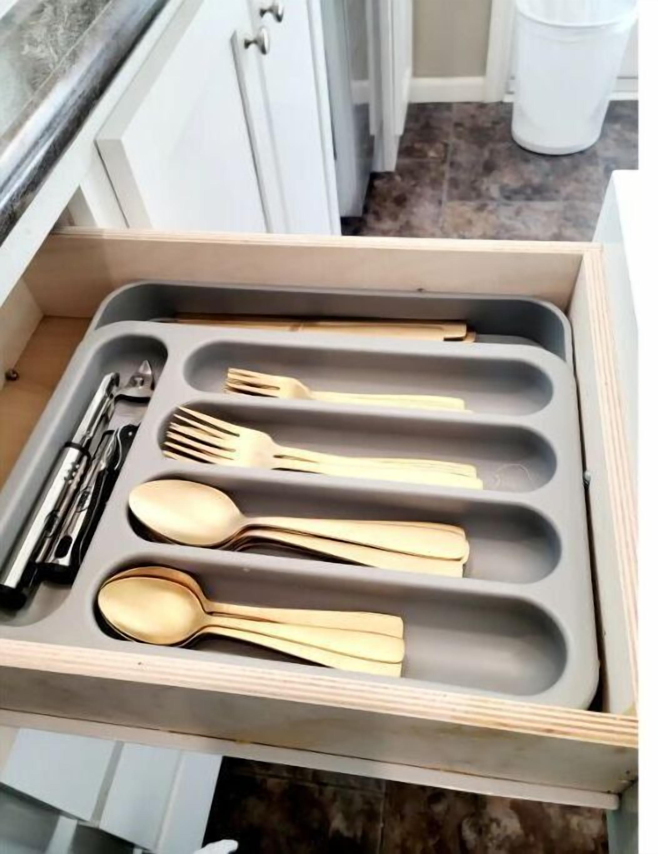 A drawer with compartments containing various utensils including spoons, forks, and a knife.