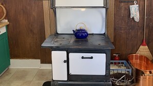 A kitchen with a stove, a window, and a broom.