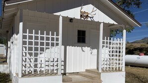 A white building with a porch, a small window, and a white picket fence.
