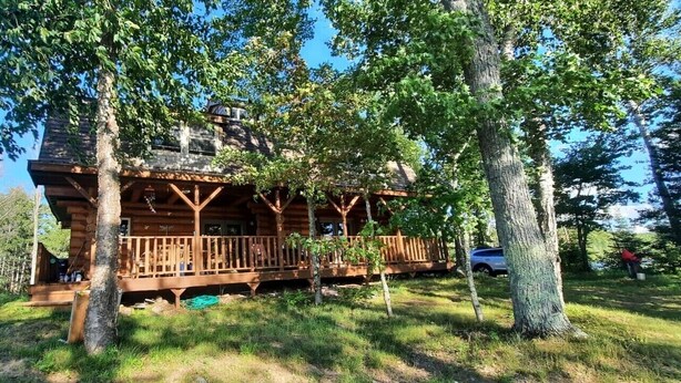 A log cabin with a porch, surrounded by trees. - Private, Family/Pet-Friendly, Log Cabin on Waterfront Chicaugon Lake Property.   (Crystal Falls)