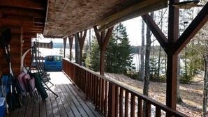A wooden deck with a railing overlooking a lake, surrounded by trees. - Private, Family/Pet-Friendly, Log Cabin on Waterfront Chicaugon Lake Property.   (Crystal Falls)