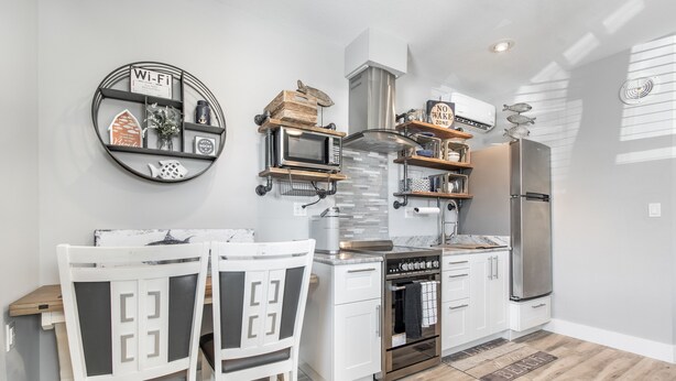 A modern kitchen with white cabinetry, a built-in oven, a stainless steel refrigerator, and a round Wi-Fi sign.
