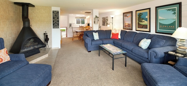 A living room with a fireplace, blue sofas, a coffee table, and framed pictures on the wall.