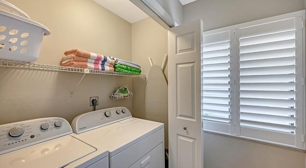 A laundry area with two white washing machines, a drying rack, and a basket.