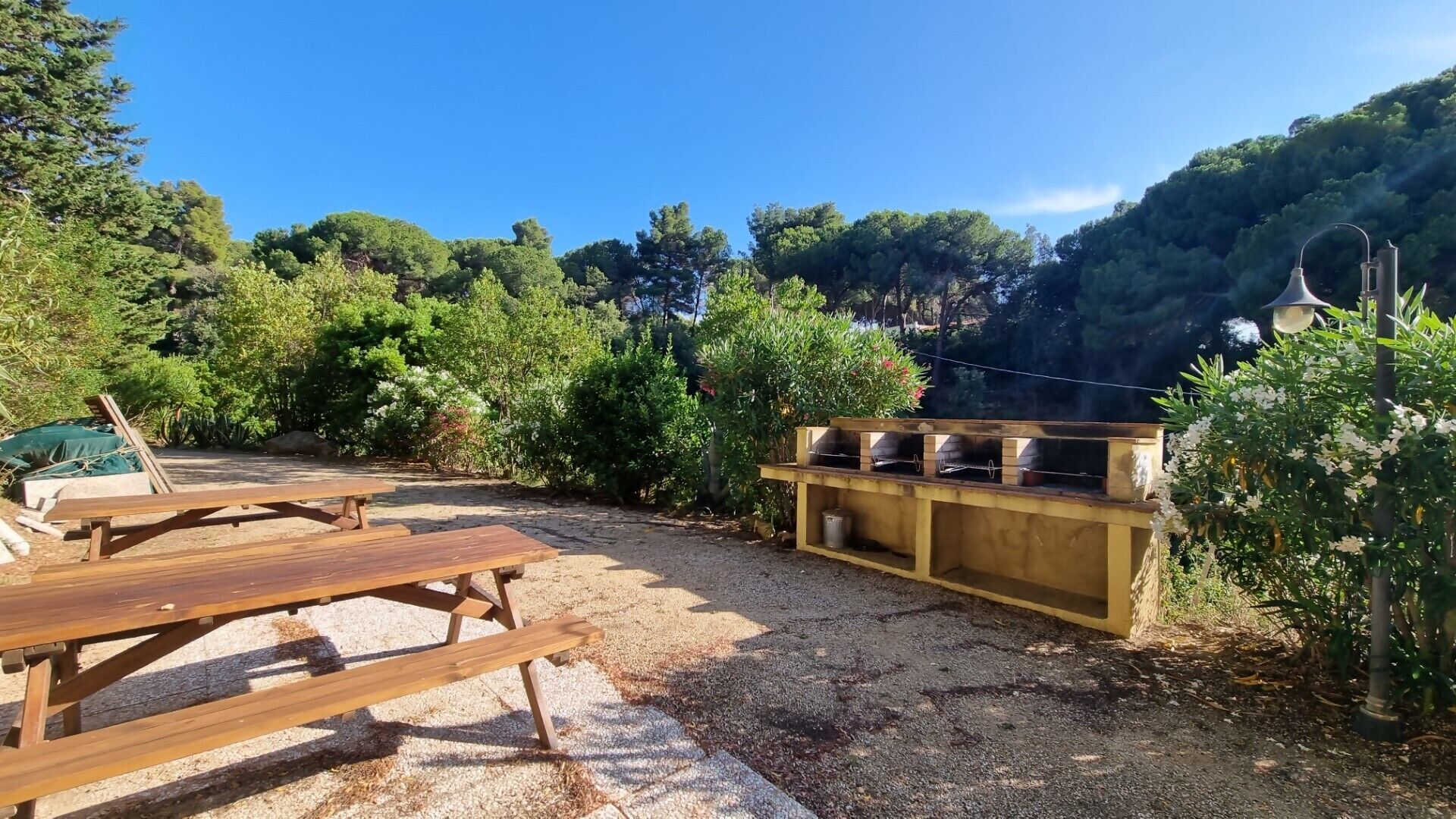 Un espace extérieur aménagé avec des tables de pique-nique, un barbecue et un lampadaire.