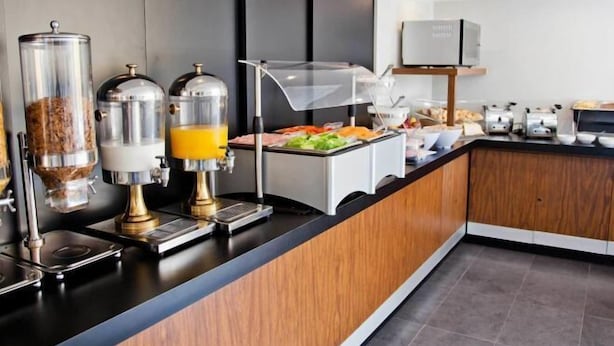 Eine moderne Frühstückstheke mit Kaffeeautomaten, einem Saftspender und einer Auswahl an Frühstücksartikeln.