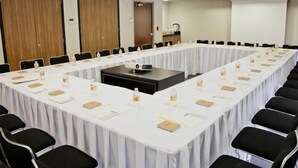 Ein Konferenzraum mit einem langen Tisch, schwarzen Stühlen und einem Projektor.