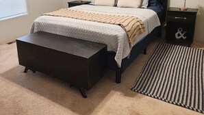 Une chambre à coucher avec un lit, des tables de chevet, un banc et un tapis.